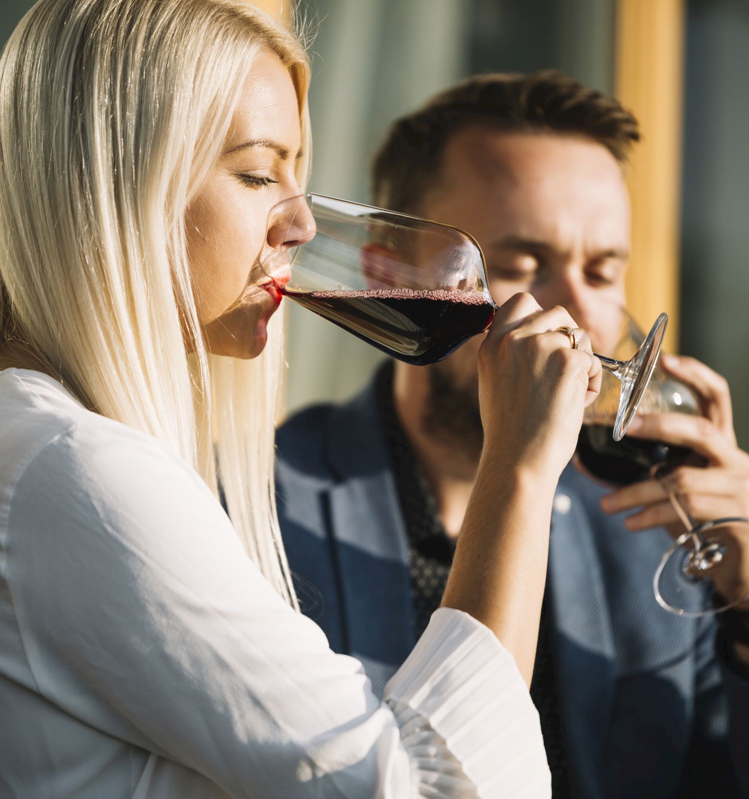 A man and a woman enjoy glasses of red wine together, both appearing relaxed as they savor their drinks in a casual setting.